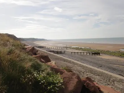 a row of benches on a beach next to the ocean at 8A Corkickle in Whitehaven