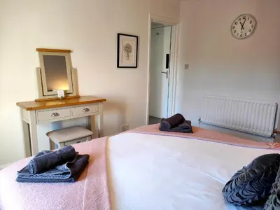 a bedroom with two beds and a desk with a mirror at Squirrel Lodge in Keswick