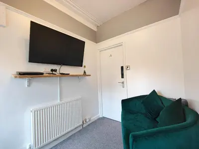 a living room with a green chair and a flat screen tv at Squirrel Lodge in Keswick