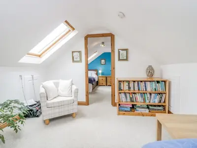 a room with a mirror and a chair and a book shelf at Shundraw Cottage in Keswick