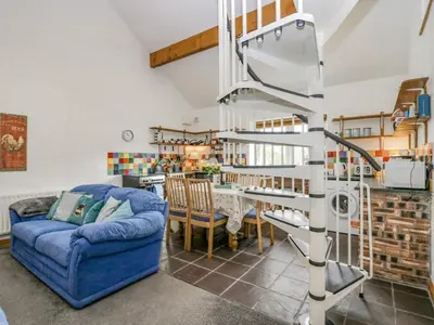 a living room with a blue couch and a spiral staircase at Shundraw Cottage in Keswick