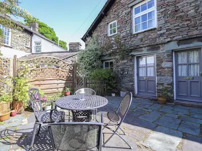 a patio with a table and chairs in front of a building at Bakers Yard Cottage in Ambleside