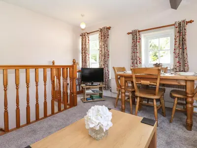 a living room with a dining room table and a television at Bakers Yard Cottage in Ambleside