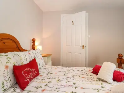 a bedroom with a bed with red pillows at Bakers Yard Cottage in Ambleside