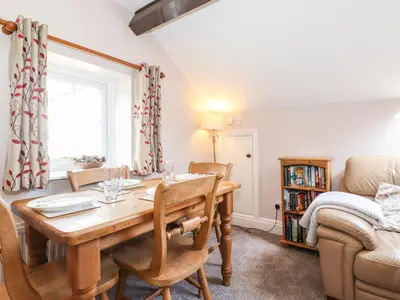 a dining room with a table and a couch at Bakers Yard Cottage in Ambleside