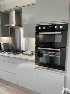 a kitchen with white cabinets and a black oven at Lovely 2 bed apartment with hot tub log burner and off street parking in Dumfries