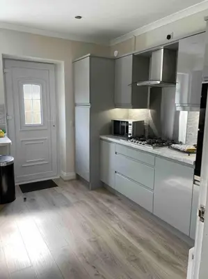 a kitchen with white cabinets and a stove top oven at Lovely 2 bed apartment with hot tub log burner and off street parking in Dumfries