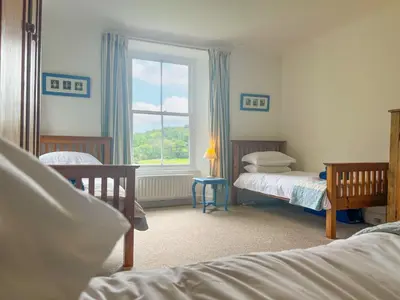 a bedroom with two beds and a window at Little Parrock, Grasmere nestled at the foot of Helm Crag with walks from the door in Grasmere