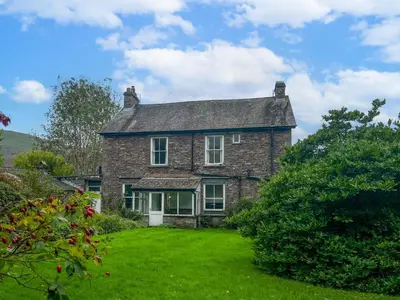 an old brick house with a green yard at Little Parrock, Grasmere nestled at the foot of Helm Crag with walks from the door in Grasmere