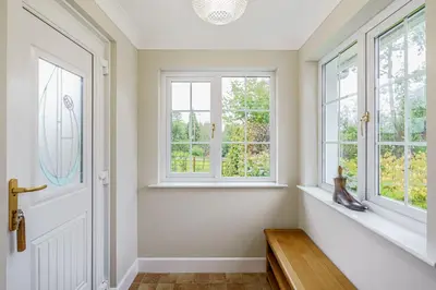 a hallway with two windows and a wooden bench at Peregrine Cottage with Hot Tub in Newton Stewart