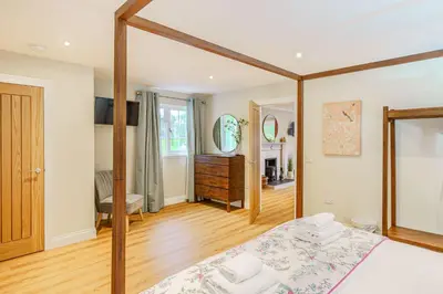 a bedroom with a bed with a wooden frame at Peregrine Cottage with Hot Tub in Newton Stewart