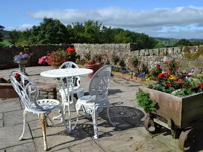 a patio with a table and two chairs and flowers at Rosedale- Lyl in Ireby