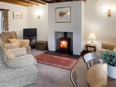 a living room with a fireplace and a couch at Ellarbeck Cottage in Caldbeck