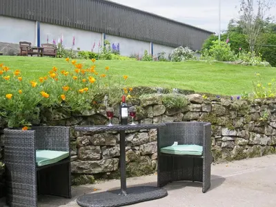 a table with two chairs and a bottle of wine at Ellarbeck Cottage in Caldbeck