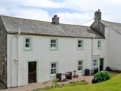 a white house with green windows and a yard at Swaledale Cottag in Caldbeck