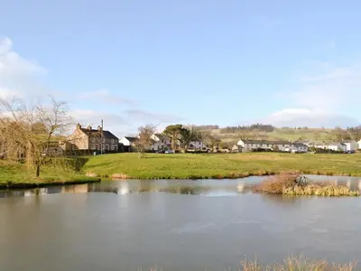 a river in a town with houses in the background at Swaledale Cottag in Caldbeck
