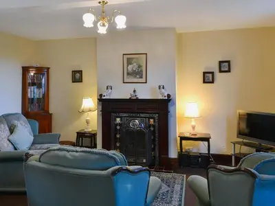a living room with blue chairs and a fireplace at The Coach House in Wetheral