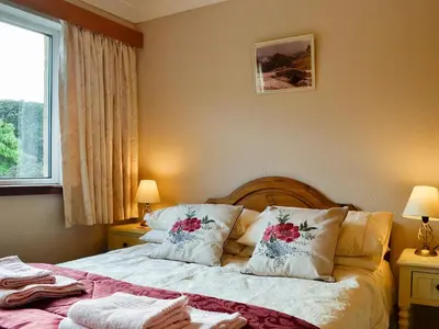 a bedroom with a bed with pillows and a window at Briar Bank Bungalow in Cockermouth