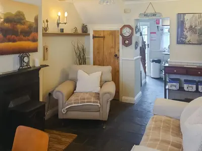 a living room with a chair and a clock at Tanner's Cottage in Cockermouth