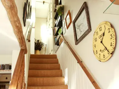 a stairway with a clock on the wall and a staircase at Tanner's Cottage in Cockermouth