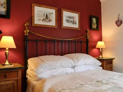 a bedroom with a bed with red walls and two lamps at Tanner's Cottage in Cockermouth