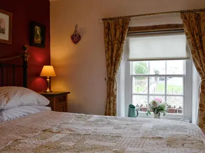 a bedroom with a bed and a window at Tanner's Cottage in Cockermouth