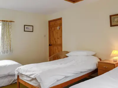 a bedroom with two beds and a wooden door at Beck Cottage in Ennerdale Bridge