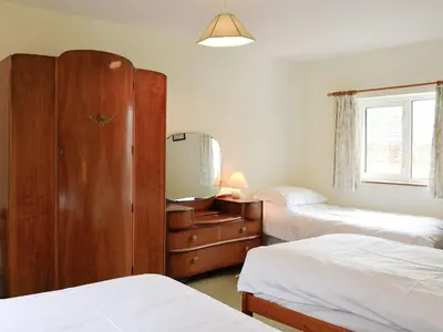 a bedroom with two beds and a dresser with a mirror at Beck Cottage in Ennerdale Bridge