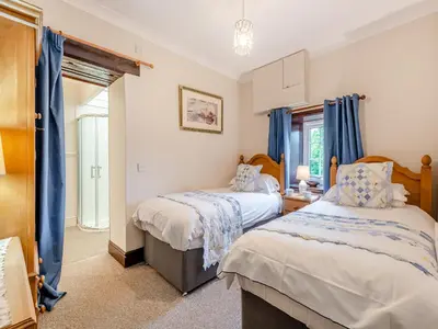two beds in a room with blue curtains at Halls Bank Farm in Plumbland