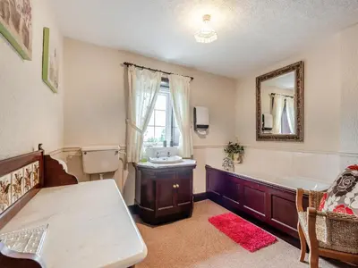 a bathroom with a tub and a sink and a mirror at Halls Bank Farm in Plumbland