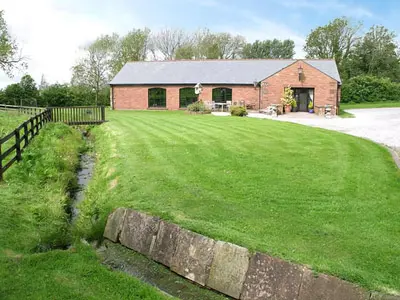 a brick house with a fence and a grass yard at Berwyn Bank in Gilcrux