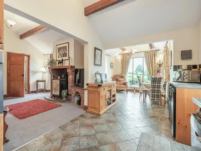 a living room with a fireplace and a table at Beckside in Gilcrux