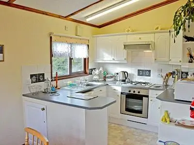 a kitchen with white cabinets and a counter top at Rosella in Bridekirk