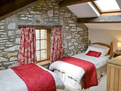 two beds in a room with a stone wall at The Corn Mill in Branthwaite