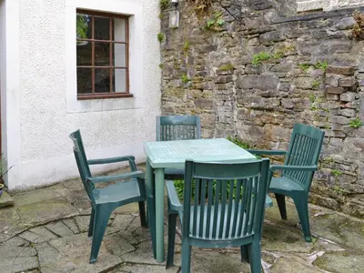 a green table and chairs in front of a building at The Corn Mill in Branthwaite