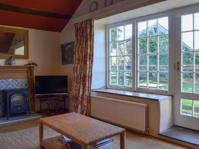a living room with a fireplace and a large window at Birkerthwaite Cottage-W41479 in Eskdale