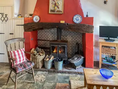 a living room with a fireplace and a chair at Birkerthwaire Stable-W41477 in Eskdale