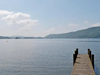 a dock on a lake with mountains in the background at Birkerthwaire Stable-W41477 in Eskdale