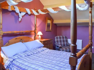 a bedroom with a canopy bed and a purple wall at Birkerthwaite Barn-W41478 in Eskdale