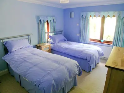 two beds in a room with blue walls and windows at Bank End in Glenridding