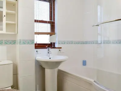 a white bathroom with a sink and a bath tub at Glenwood - 18630 in Keswick