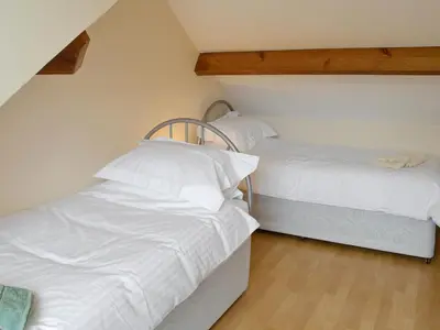 two beds in a room with white sheets at Skiddaw View in Keswick