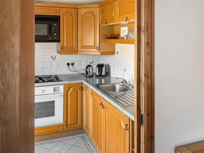 a kitchen with wooden cabinets and a sink at Leatheswater in Thirlmere