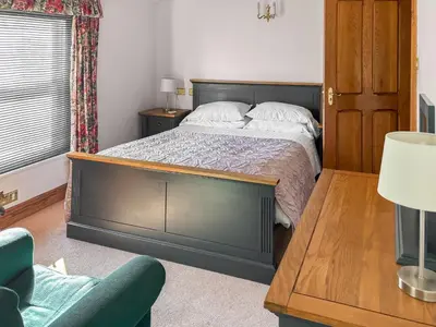 a bedroom with a large bed and a chair at Leatheswater in Thirlmere
