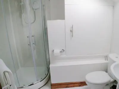 a white bathroom with a shower and a toilet at Jebel Kasr in Braithwaite