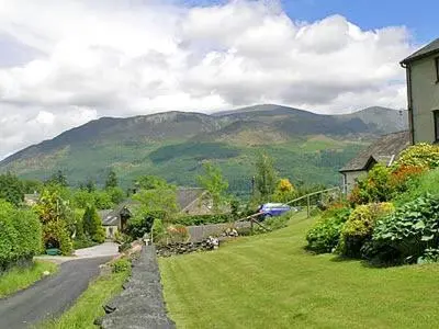 a house and a road with mountains in the background at Jebel Kasr in Braithwaite