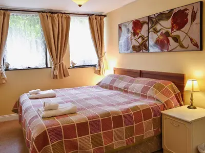 a bedroom with a bed and two windows at Little Beck in Troutbeck