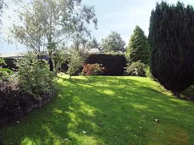 a yard with a green lawn with trees and bushes at Little Beck in Troutbeck