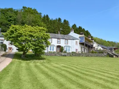 a large white house with a tree in a field at Load Pot in Watermillock