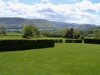 a green lawn with a view of a lake and mountains at The Carriage House in Watermillock